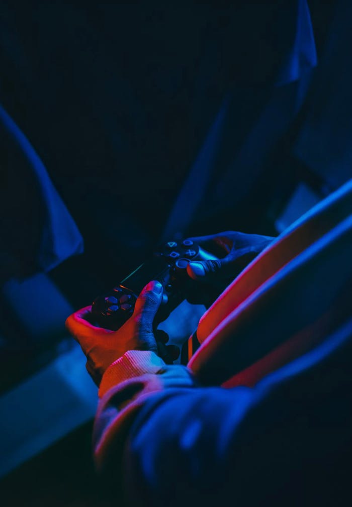 menu-06 Close-up of a person holding a gaming controller under neon lighting. Ideal for gaming and technology themes.